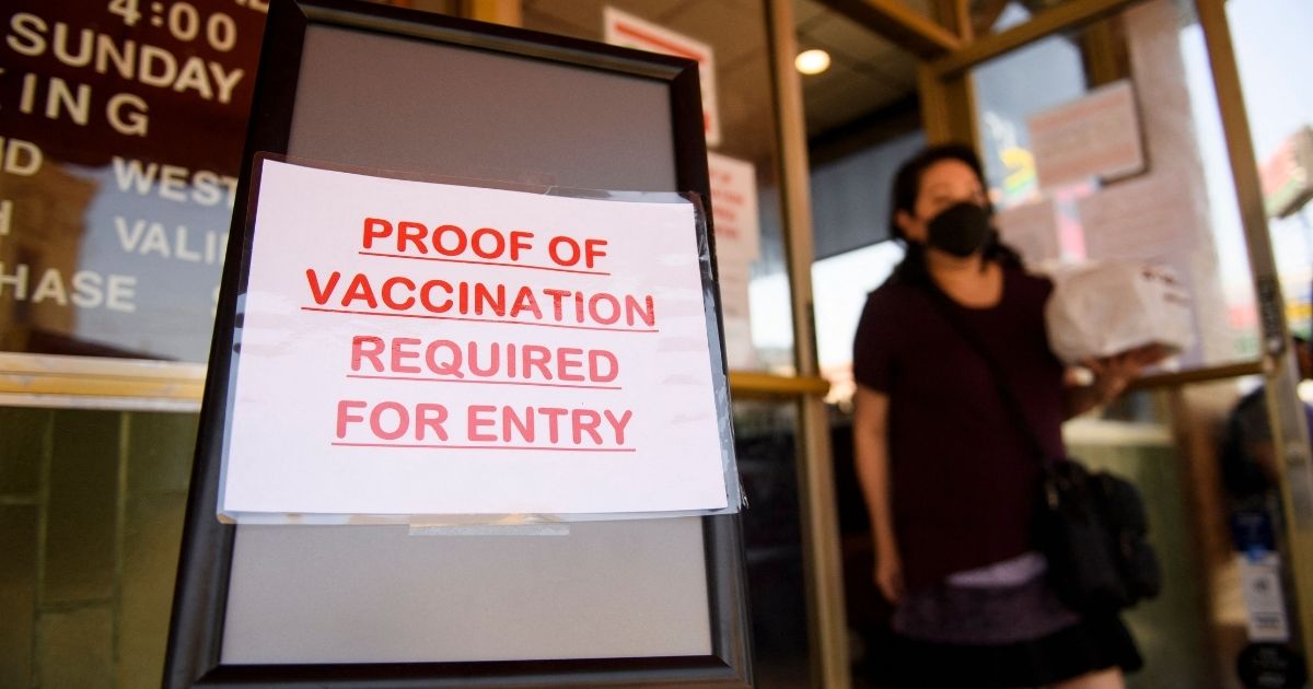 A sign stating proof of a COVID-19 vaccination is required is displayed outside of Langer's Deli in Los Angeles on Aug. 7.