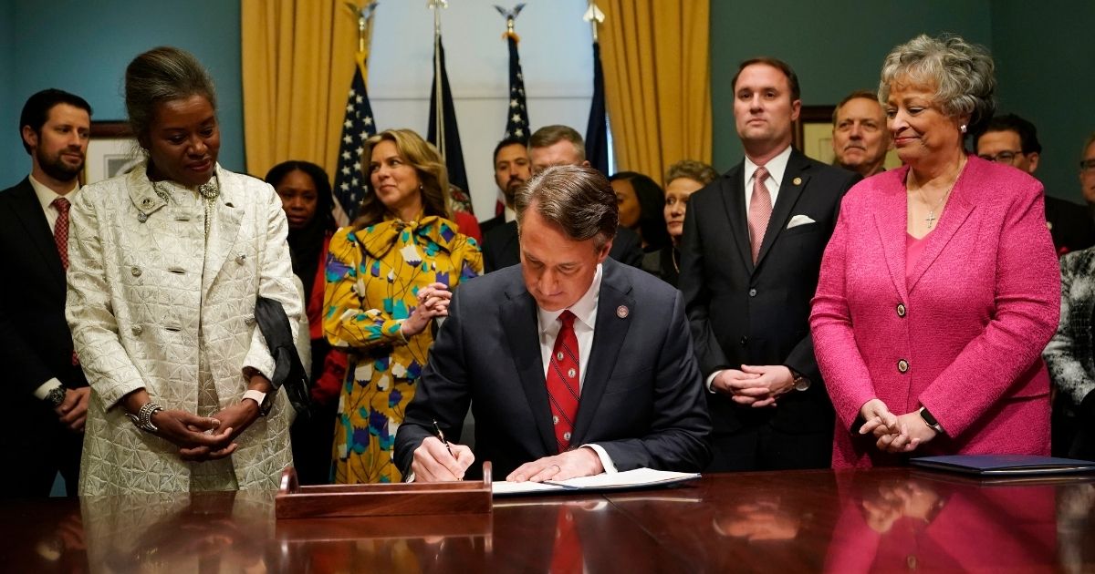 On Saturday, Virginia's newly sworn in GOP Gov. Glenn Youngkin, center, signed 11 executive orders in the Governors conference room of the Capitol in Richmond, Virginia, while L. Gov. Winsome Earle-Sears, left, and Secretary of the Commonwealth Kay Cole James, right, watched.
