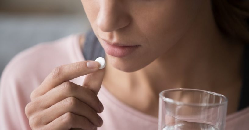 A woman takes a pill in this stock image.