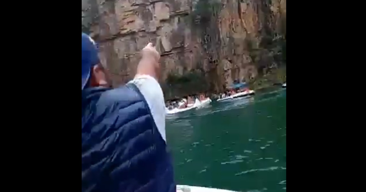 A man points just before a rock collapse at a lake in southeastern Brazil.