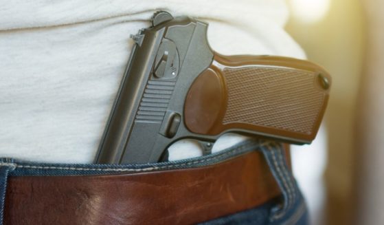 A man carries a gun in this stock image.