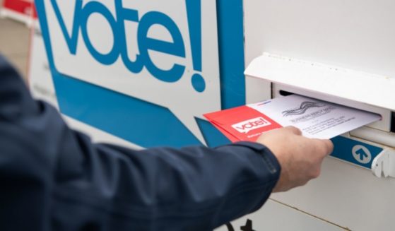 A voter places a ballot in a drop box in this stock image.