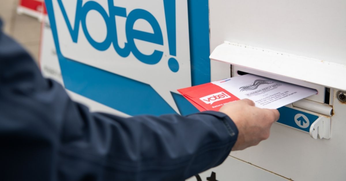 A voter places a ballot in a drop box in this stock image.