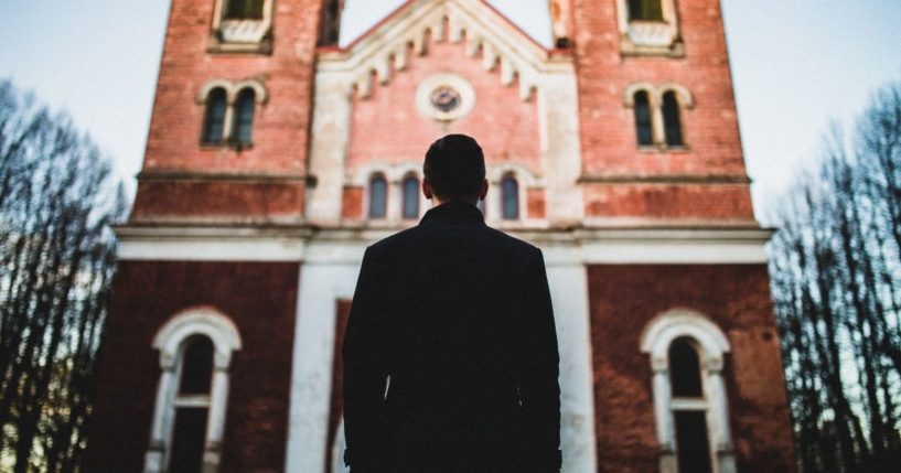 A man stands outside a church in the above stock image.