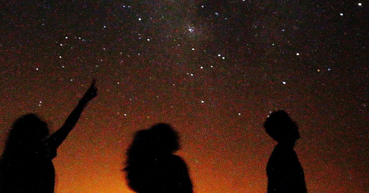 Friends look at the Milky Way galaxy rising in the night sky in Kuwait's al-Salmi desert.