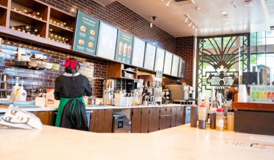Low-angle view of drink order and mobile order pickup area at Starbucks coffee with baristas visible working behind a counter in Alameda, California, on October 16, 2021.
