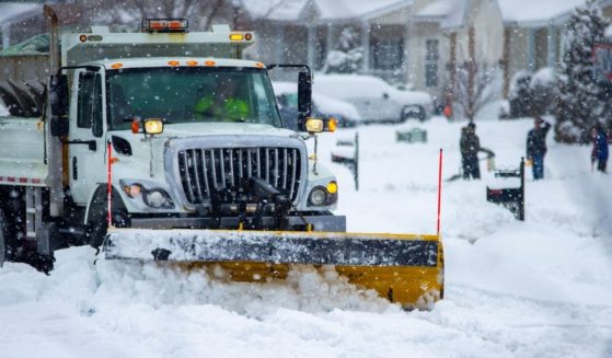 A snow plow clears a road in the above stock image.