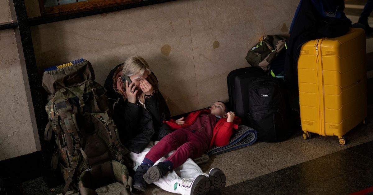 A mother and her daughter wait for a train in Kyiv, Ukraine, as they attempt to leave on Thursday after Russian troops began their assault on the country. Many are trying to flee the capital city in any way they can, flooding the train stations and backing up the roads.
