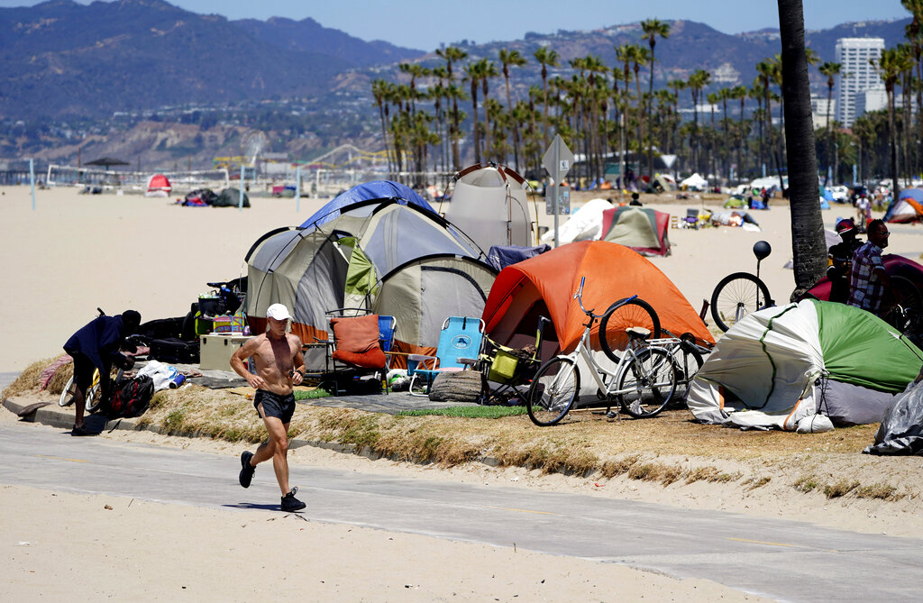A jogger runs past a homeless encampment in the Venice Beach section of Los Angeles in this file photo from June 2021. Local residents say homeless encampments are being relocated to less-visible sites in advance of the Super Bowl.