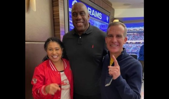 San Francisco Mayor London Breed, left, and Los Angeles Mayor Eric Garcetti, right, pose maskless with NBA legend Magic Johnson during the NFC championship game Sunday in LA.