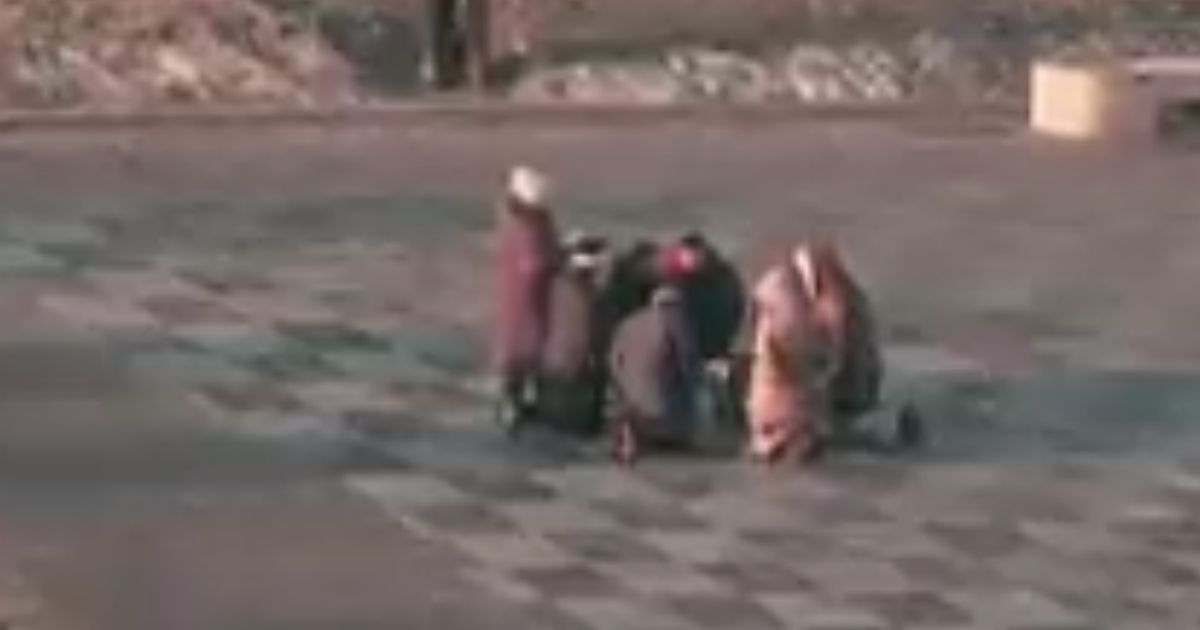 A small group of of people is seen gathering in the morning to kneel on the cold pavement of the main square in Kharkiv to pray as Russian troops advance.