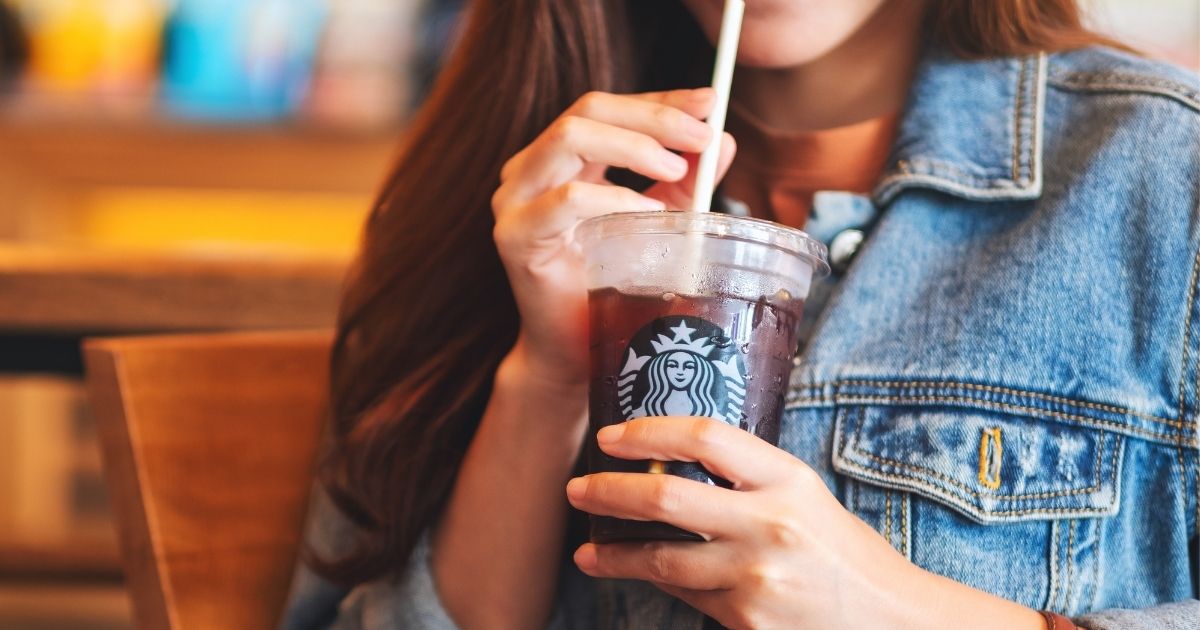 A young woman drinks an iced coffee at Starbucks.