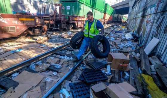 Contract worker Adam Rodriguez recovers vehicle tires from the shredded boxes and packages along a section of the Union Pacific train tracks in downtown Los Angeles in a file photo from January. Authorities say dozens of handguns and shotguns were among items stolen by thieves who have raided cargo containers aboard trains near downtown Los Angeles for months.