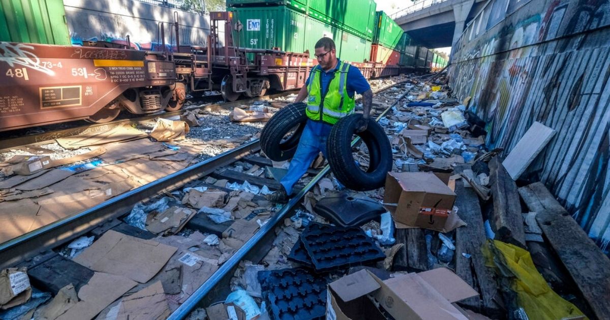 Contract worker Adam Rodriguez recovers vehicle tires from the shredded boxes and packages along a section of the Union Pacific train tracks in downtown Los Angeles in a file photo from January. Authorities say dozens of handguns and shotguns were among items stolen by thieves who have raided cargo containers aboard trains near downtown Los Angeles for months.