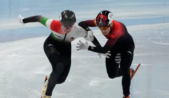 Shaolin Sandor Liu, left, of Hungary and Ren Ziwei of China, battle to cross the finish line in the final of the men's 1,000-meter during the short track speedskating competition at the 2022 Winter Olympics on Monday.