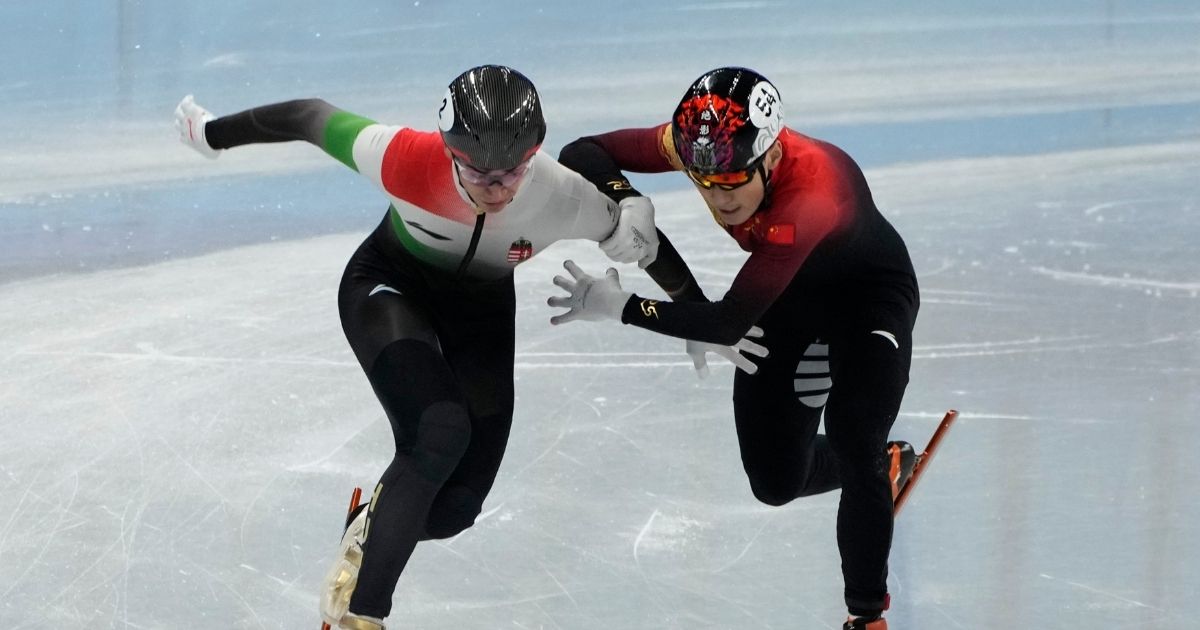 Shaolin Sandor Liu, left, of Hungary and Ren Ziwei of China, battle to cross the finish line in the final of the men's 1,000-meter during the short track speedskating competition at the 2022 Winter Olympics on Monday.
