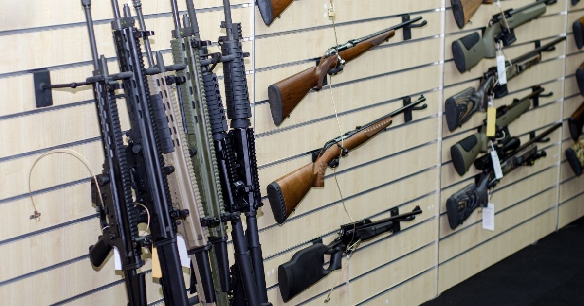 Guns hang on a wall at a gun shop.