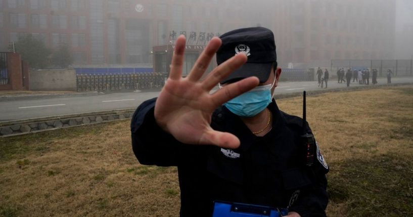 A security guard moves journalists away from the Wuhan Institute of Virology after a World Health Organization team arrived for a field visit in Wuhan, China, in February 2021.