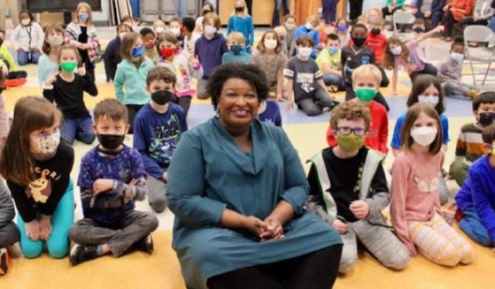 Georgia Democratic contender for governor Stacey Abrama appears in a photo without a mask, in a crowd of masked children at a Georgia elementary school.