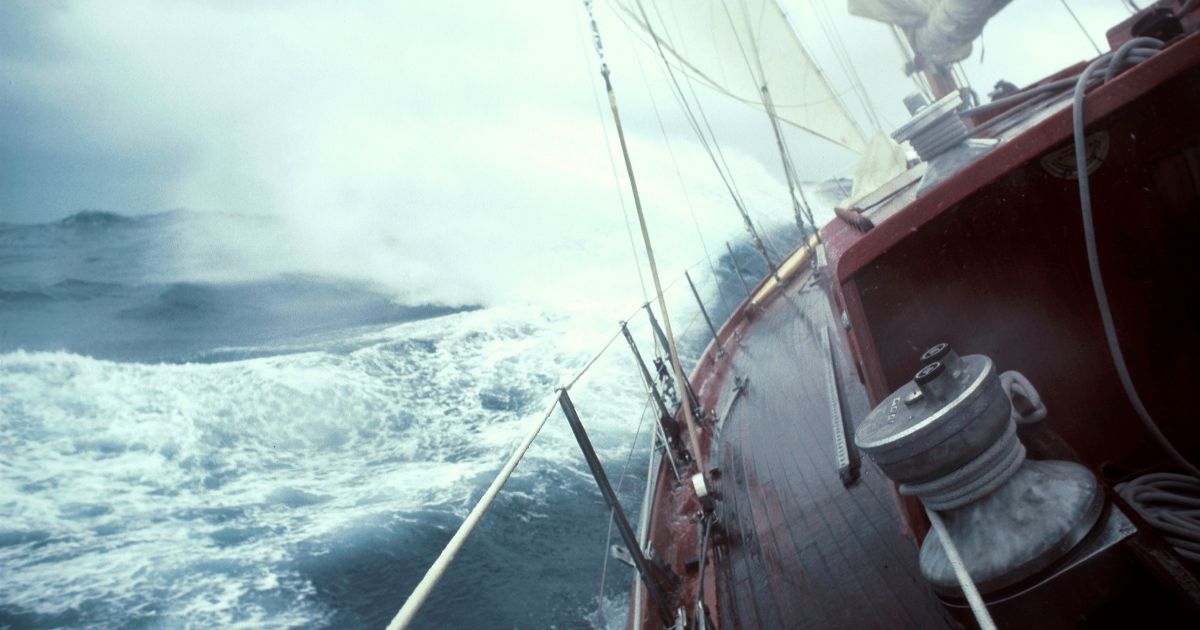 A boat sails in rough seas in the above stock image.