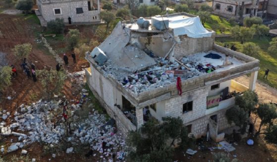 Residents on the ground are pictured in an aerial view of the the building badly damaged in a U.S. special forces raid Thursday in northern Syria.
