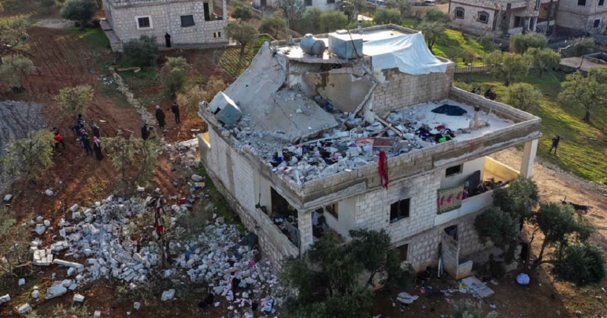 Residents on the ground are pictured in an aerial view of the the building badly damaged in a U.S. special forces raid Thursday in northern Syria.