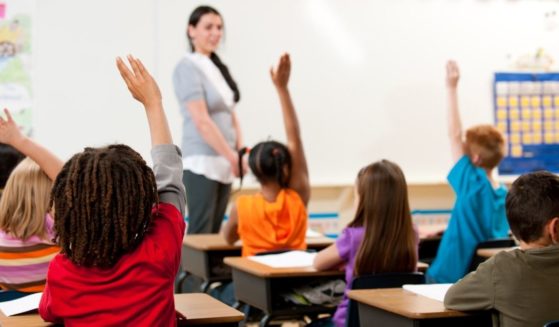 Children raise their hand in a classroom in this stock image.