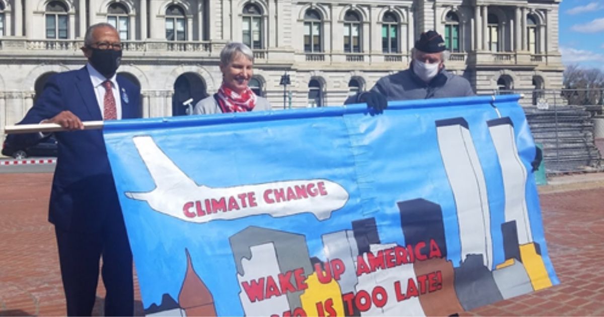 New York state Sens. Rachel May and Robert Jackson hold up a banner comparing climate change to the 9/11 terrorist attacks.
