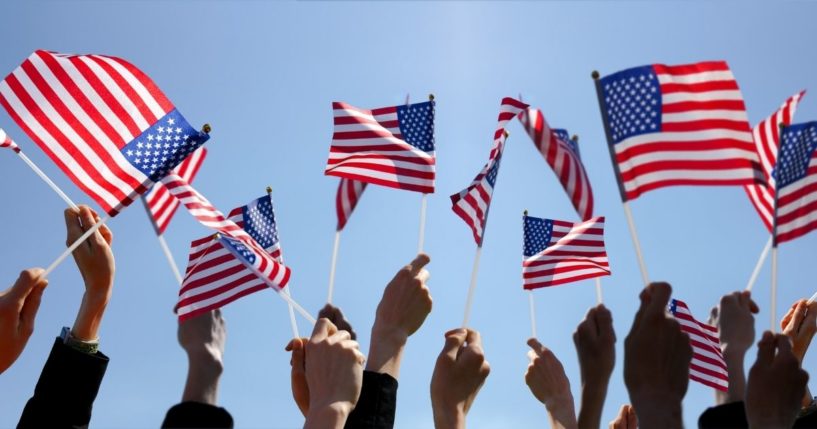People wave American flags in the above stock image.