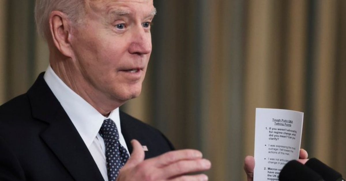 President Joe Biden holds a cheat sheet with anticipated questions and answers while meeting with reporters on Monday.