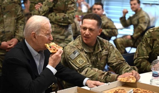 President Joe Biden takes a bite of pizza during a visit with soldiers from the 82nd Airborne Division in Rzeszow, Poland, on Friday.