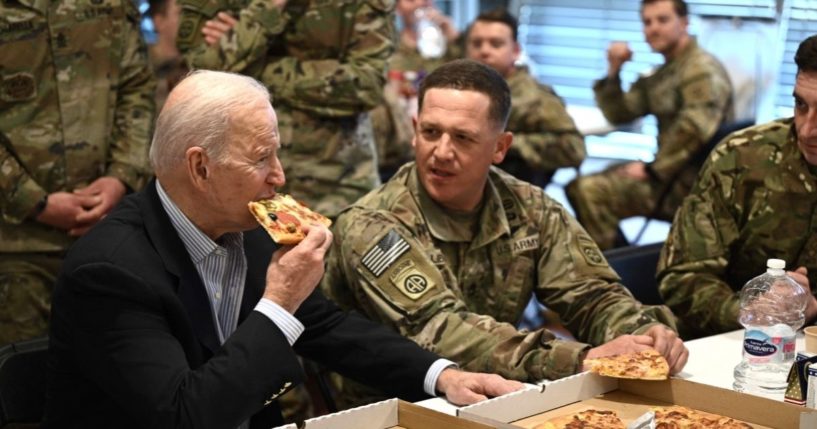 President Joe Biden takes a bite of pizza during a visit with soldiers from the 82nd Airborne Division in Rzeszow, Poland, on Friday.