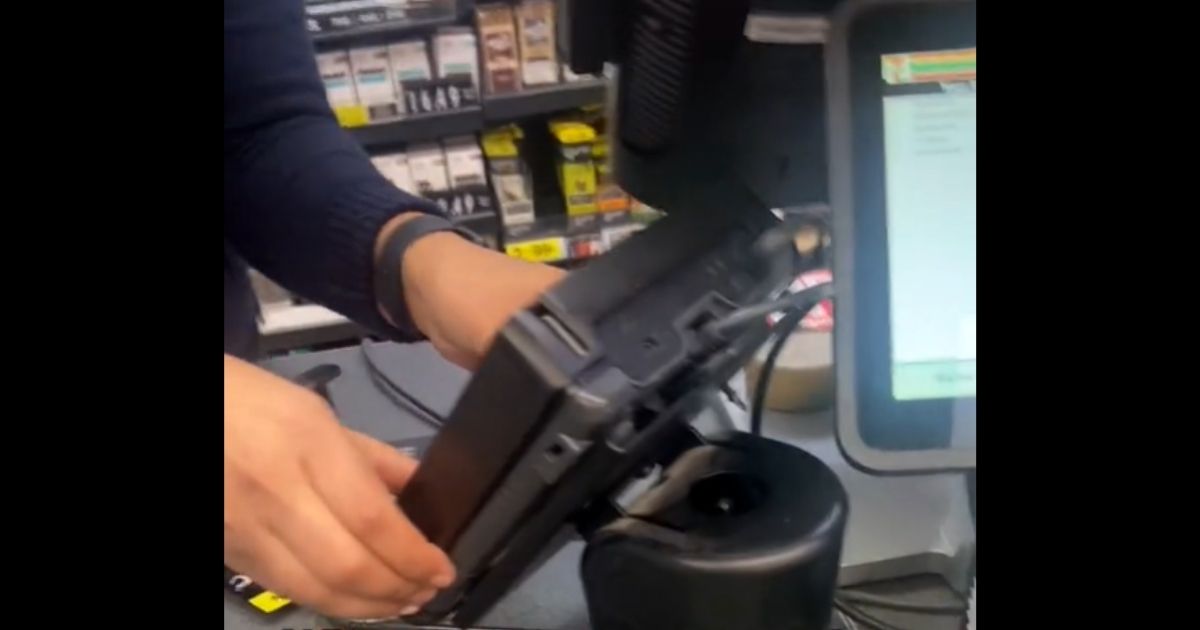 Nyshje Rattler of McKinney, Texas, rips a credit-card skimmer off a card reader at a local 7-Eleven.