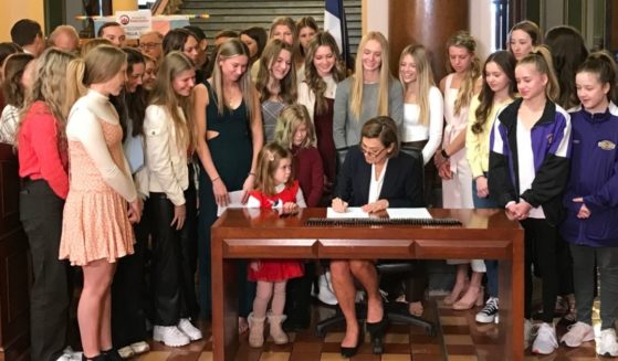 Iowa Gov. Kim Reynolds, seated at center, signs a bill allowing only those born female to compete in women's and girls' sports in the state.
