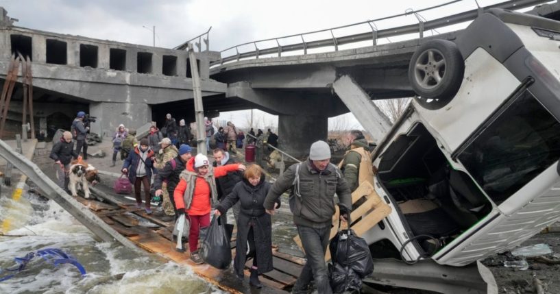 On Monday, Ukrainians cross under a destroyed bridge in Irpin, Ukraine, while trying to flee the town which has been under attack from the Russians.