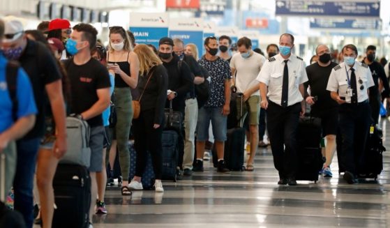 Passengers and flight crew at O'Hare International Airport in Chicago, Illinois, wait to get through security wearing masks, in accordance with the federal mask mandate, on July 1, 2021.