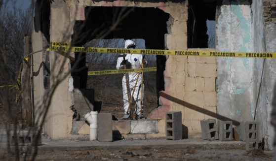 A forensic technician stands inside a ruined house where bodies were ripped apart and incinerated, on a plot of land referred to as a cartel "extermination site", on the outskirts of Nuevo Laredo, Mexico.