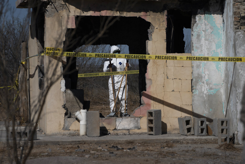 A forensic technician stands inside a ruined house where bodies were ripped apart and incinerated, on a plot of land referred to as a cartel "extermination site", on the outskirts of Nuevo Laredo, Mexico.