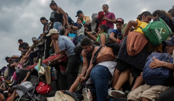 On Nov. 17, 2021, migrants help other migrants onto the bed of a trailer traveling near Jesus Carranza, Mexico, as the caravan travels north to the Mexico-American border.
