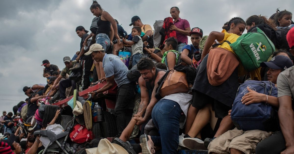 On Nov. 17, 2021, migrants help other migrants onto the bed of a trailer traveling near Jesus Carranza, Mexico, as the caravan travels north to the Mexico-American border.