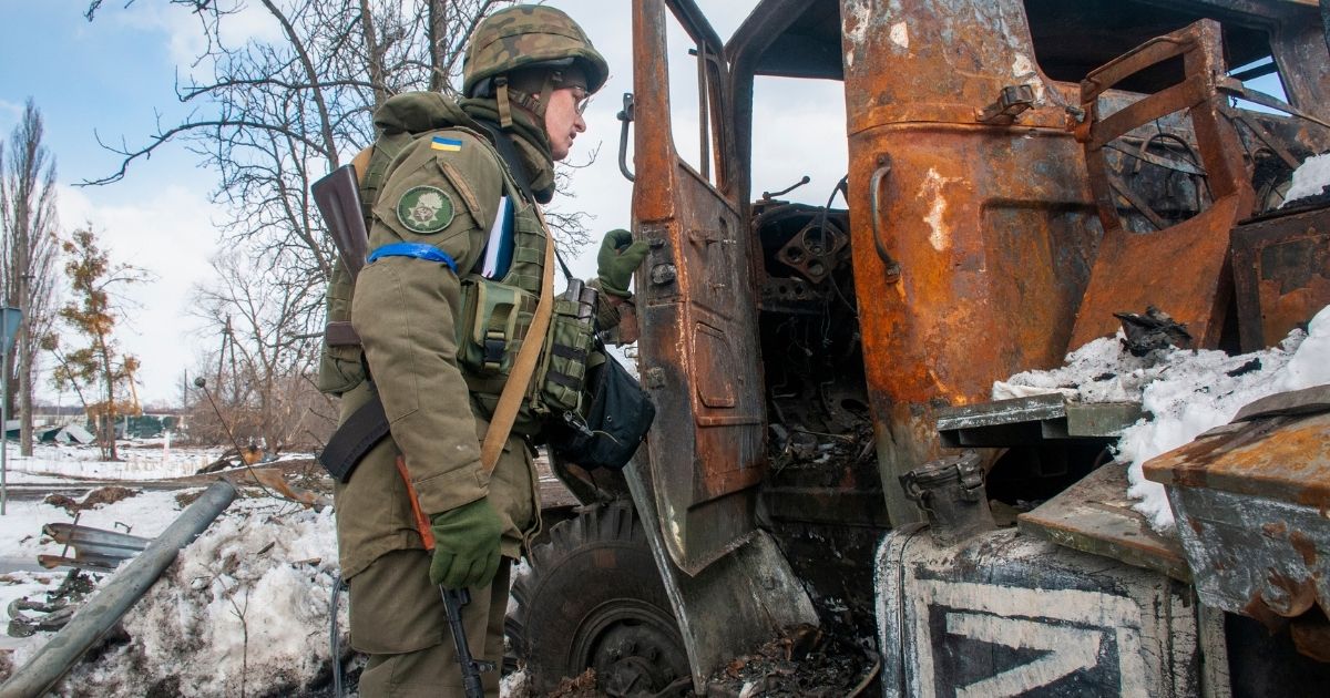 A Ukrainian National guard soldier inspects a Russian damaged military vehicle