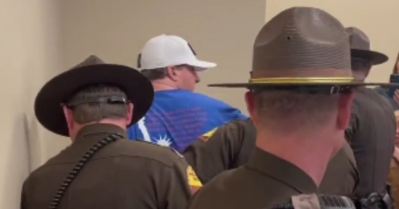 A man was taken into custody during a Tuesday night Utah Senate committee meeting after he refused to remove a sticker that read "Vote yes on HB60."