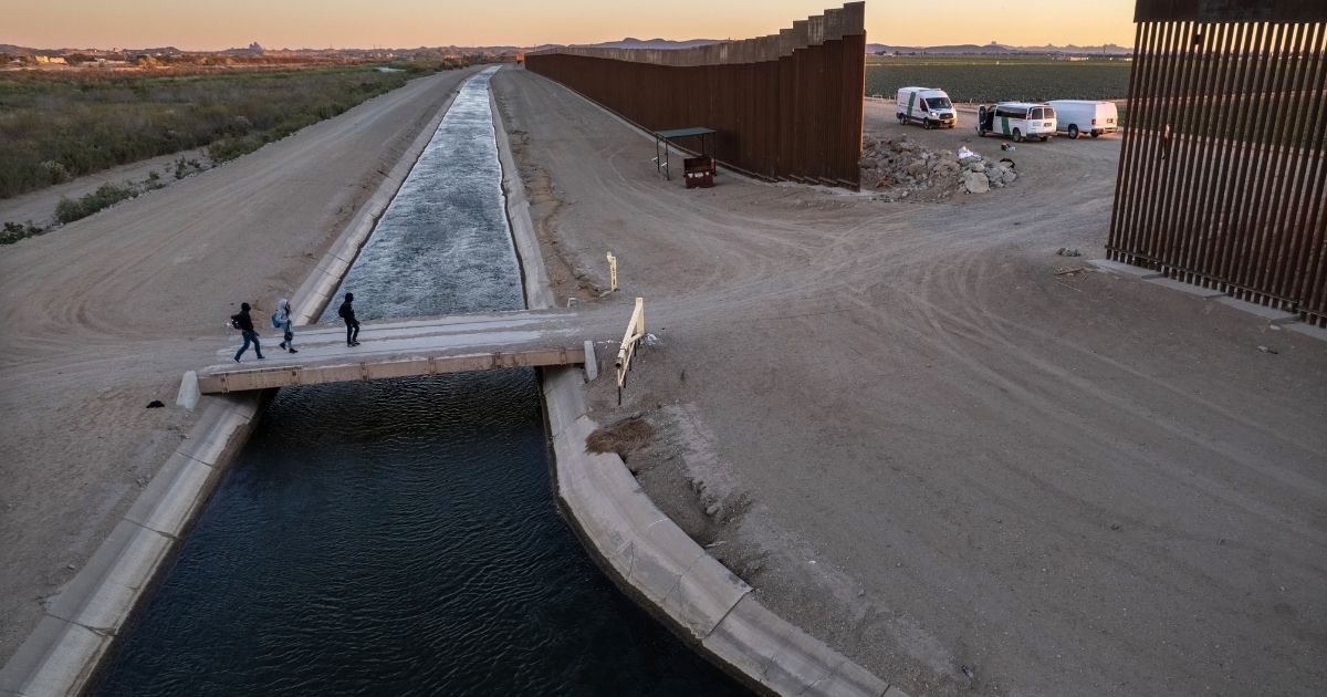 Illegal immigrants walk toward a gap in the U.S. border wall from Mexico on Dec. 11, 2021, in Yuma, Arizona.