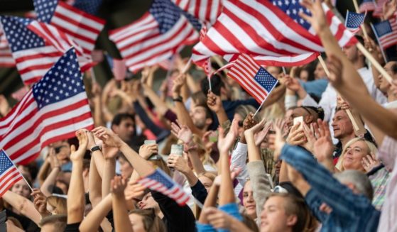 A crowd waves American flags in this stock image.