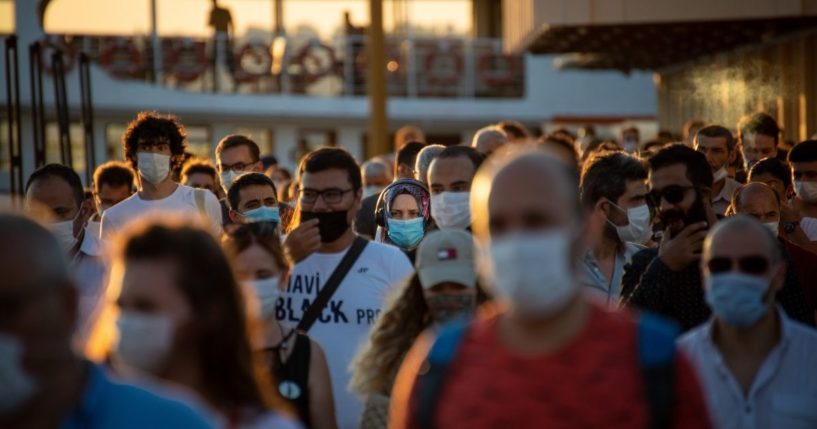 A crowd of people wearing masks is seen in this stock image.