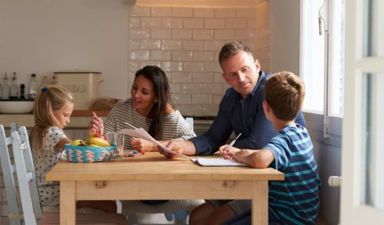 A family sits at a table in the above stock image.