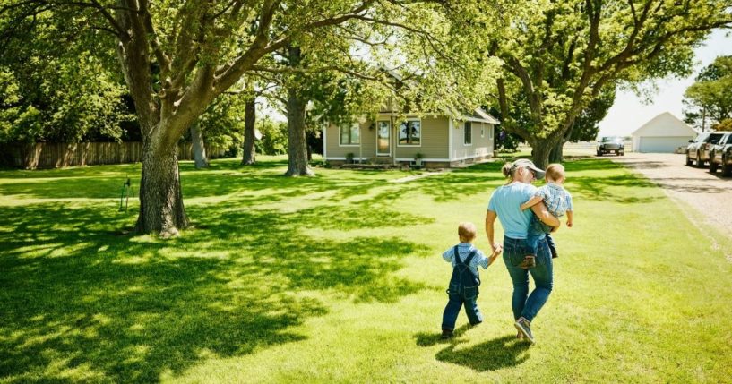 A woman walks with children through a yard in the above stock image.