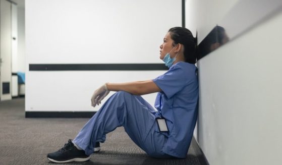 A nurse sits in a hallway in the above stock image.