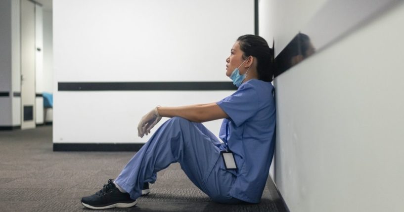 A nurse sits in a hallway in the above stock image.