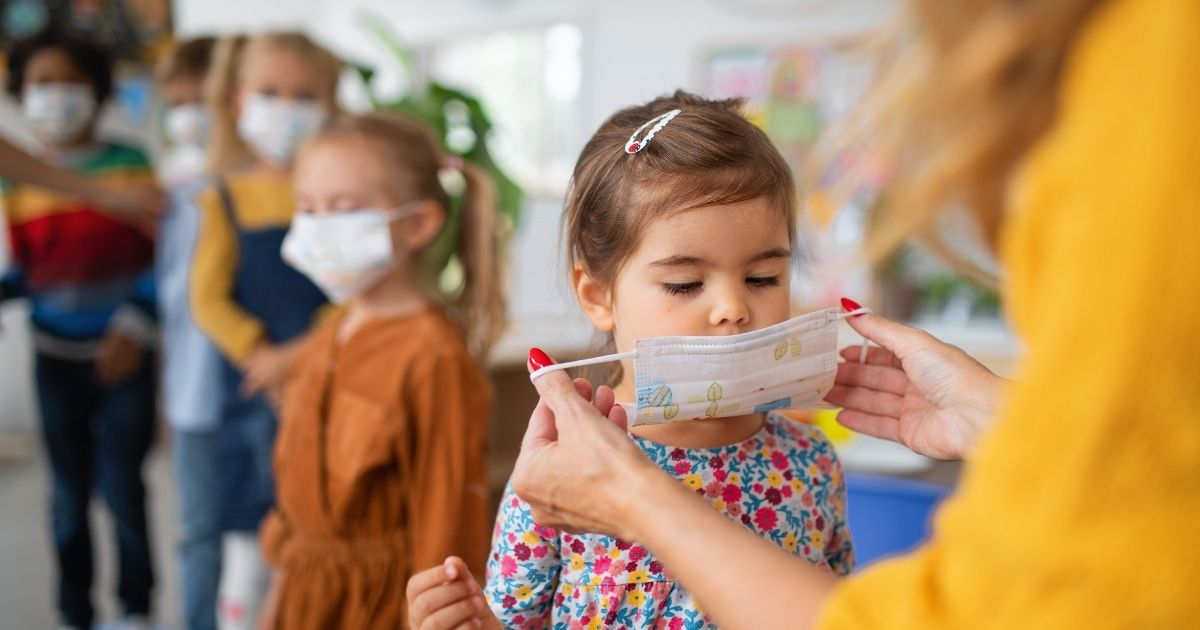 A woman puts a mask on a child in this stock image.